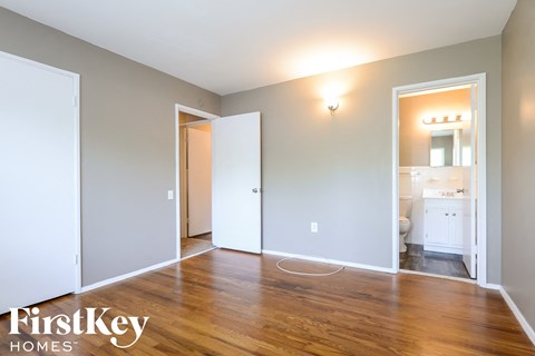 a living room with a hardwood floor and a doorway to a bathroom
