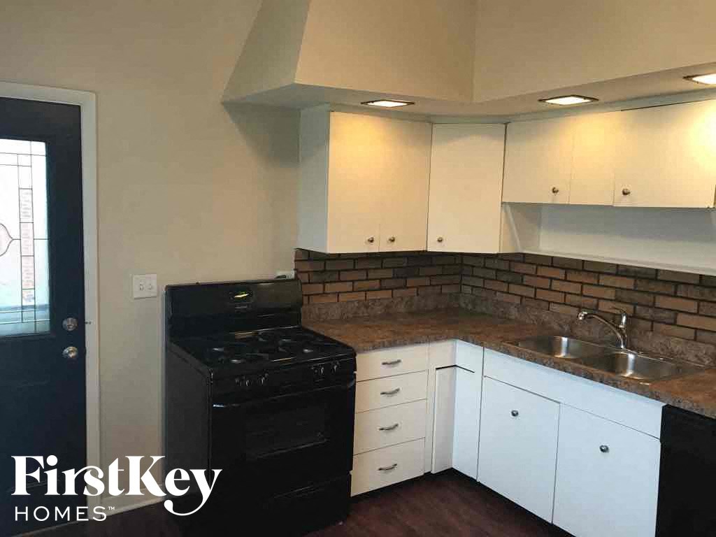 an empty kitchen with white cabinets and a black stove