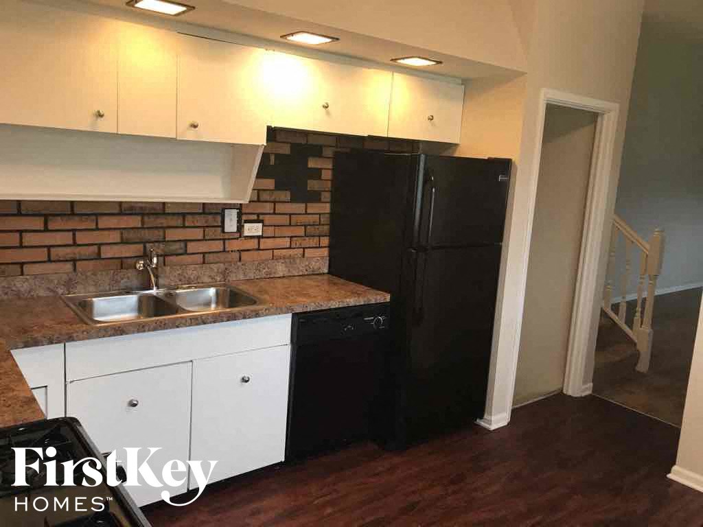 a small kitchen with a black refrigerator and white cabinets