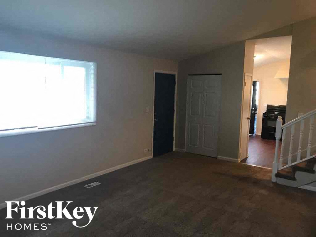 an empty living room with a staircase and a window