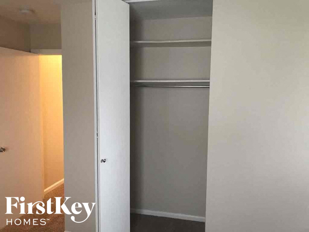 a walk in closet with a white wall and a sliding closet door