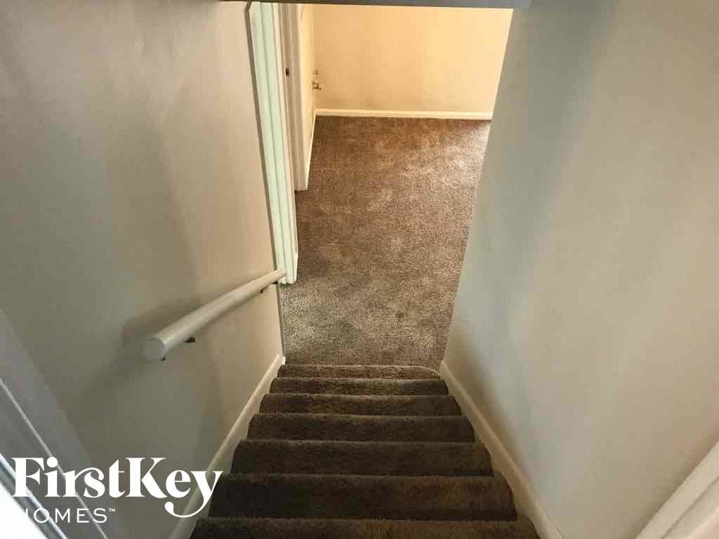 a stairwell with carpeted stairs and a white railing up the stairs