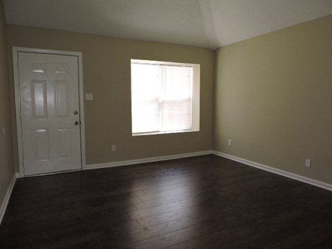 an empty living room with wooden floors and a white door