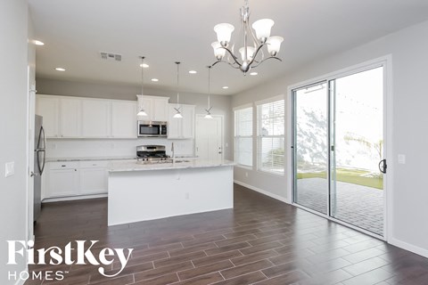 a white kitchen with white cabinets and a sliding glass door