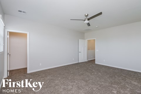 a bedroom with white walls and a ceiling fan
