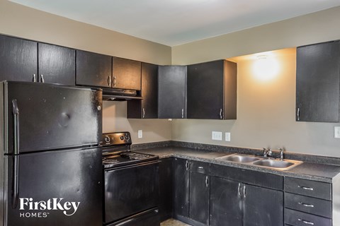 A black fridge in a kitchen with the words "FirstKey Homes" on it.