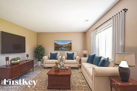 A living room with a couch, a chair, a coffee table, and a painting on the wall.
