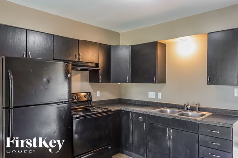 A kitchen with black cabinets and a stainless steel refrigerator.