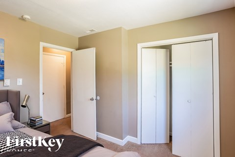 A bedroom with a bed, nightstand, and two closets.