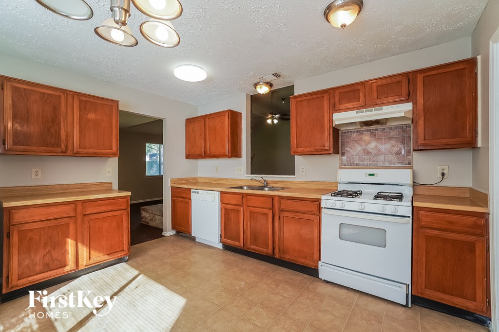 an empty kitchen with white appliances and wooden cabinets