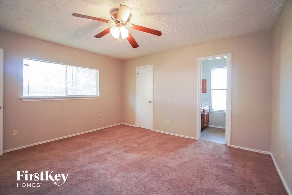 an empty living room with a ceiling fan and a window