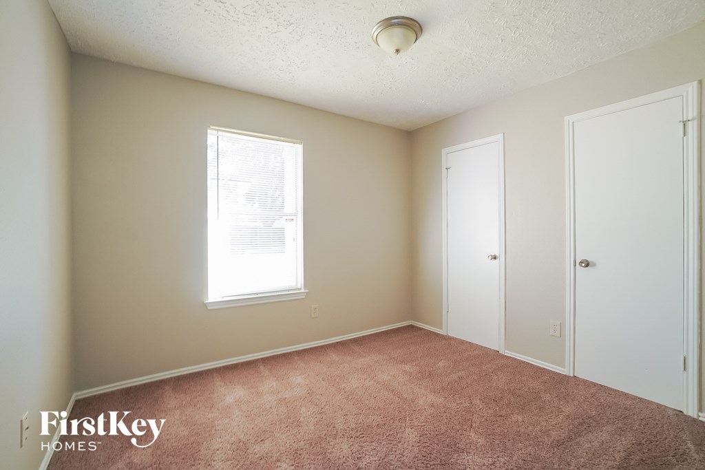 a bedroom with a carpet and two doors and a window