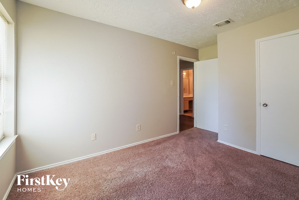 an empty living room with carpet and a door to a bathroom