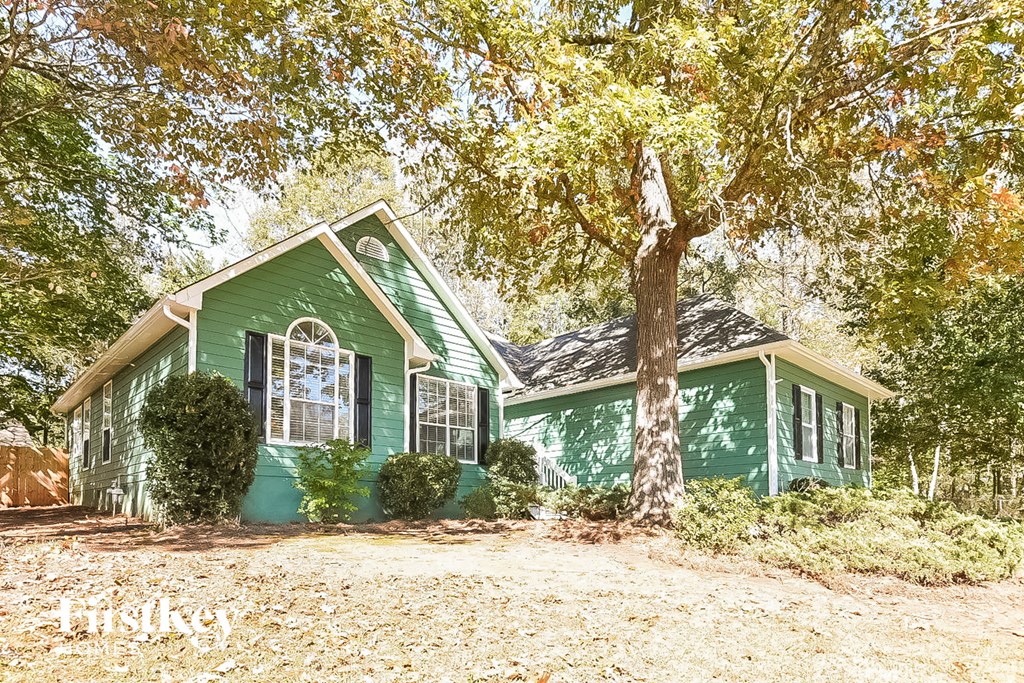 a green house with a large tree in front of it