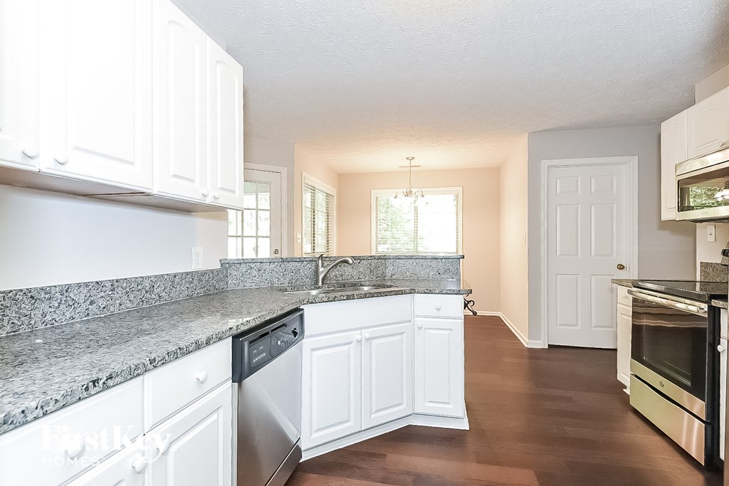 a kitchen with white cabinets and granite counter tops