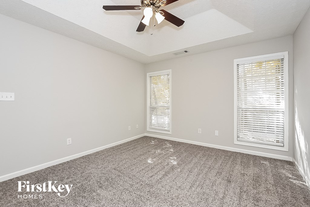 an empty living room with a ceiling fan and a window