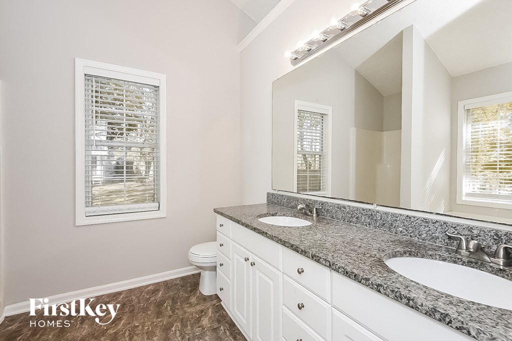 a bathroom with two sinks and a toilet and a mirror