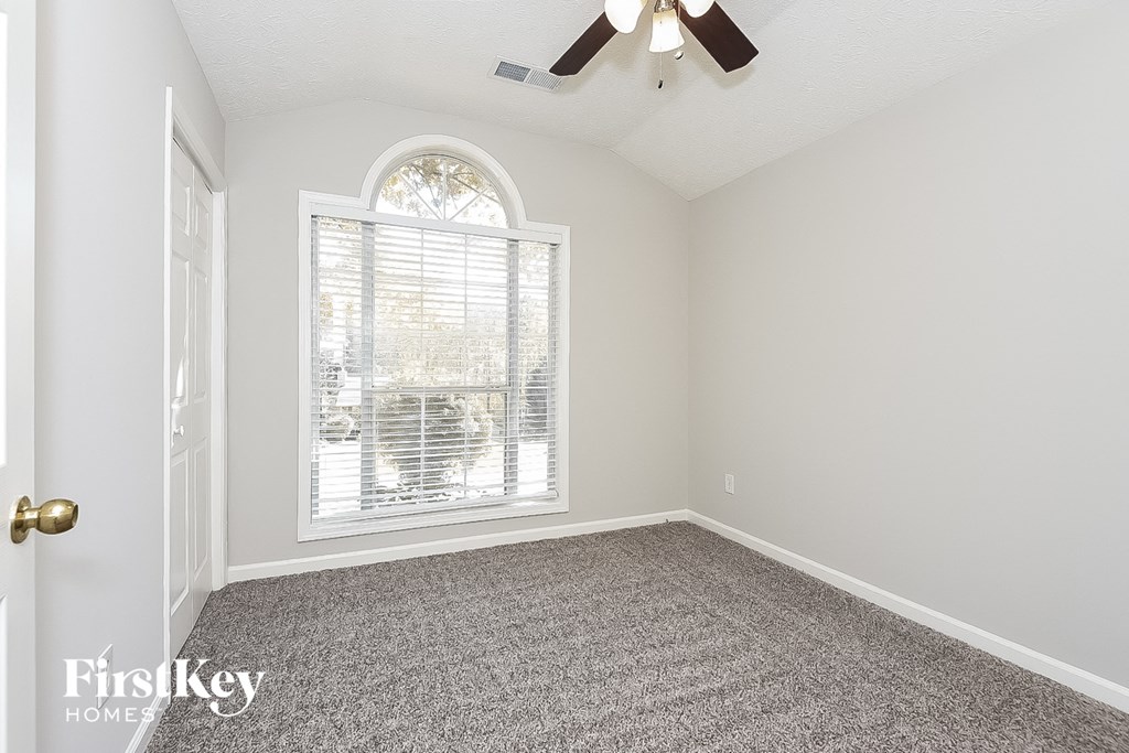 an empty bedroom with a window and a ceiling fan