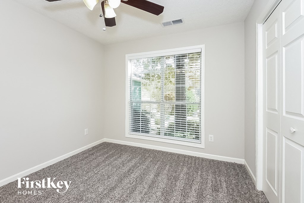 an empty bedroom with a large window and carpet