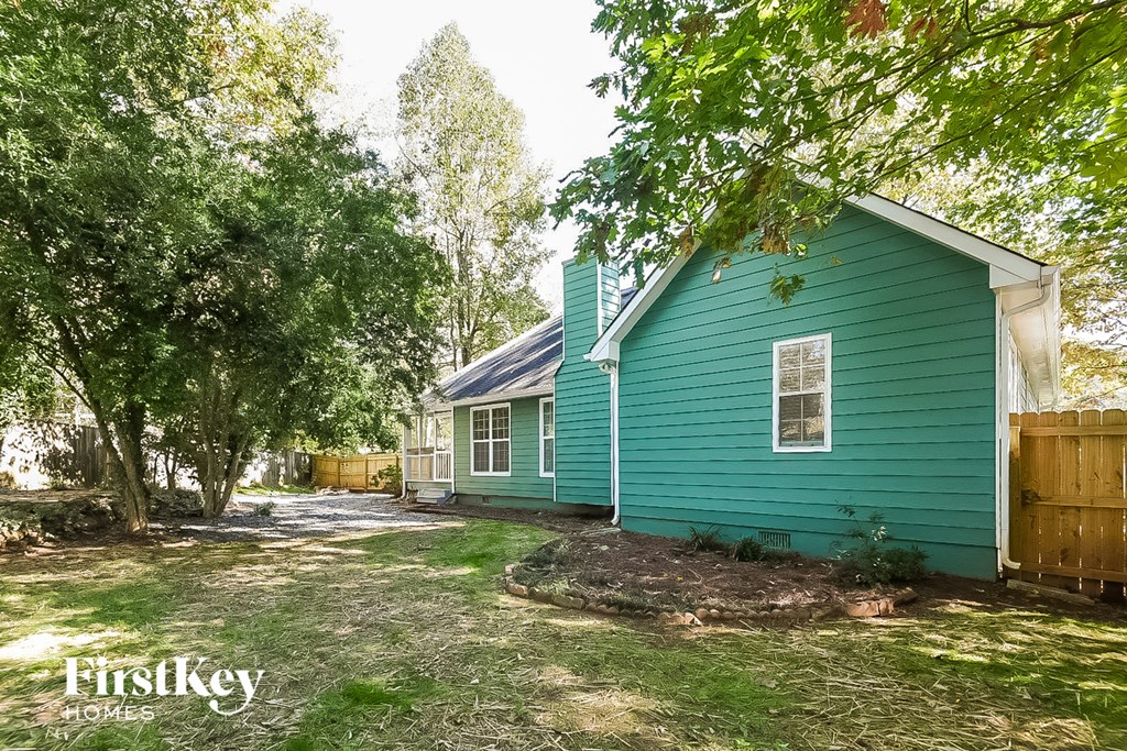 the exterior of a blue house with trees and a wood fence