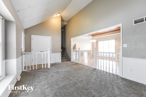 a living room with a carpeted floor and a staircase