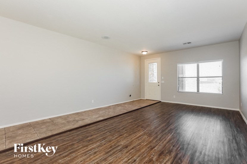 the spacious living room with wood flooring and white walls