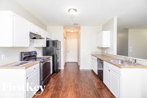 a kitchen with white cabinets and black appliances and a wood floor