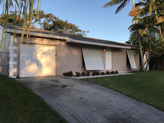 a house with a garage door and palm trees