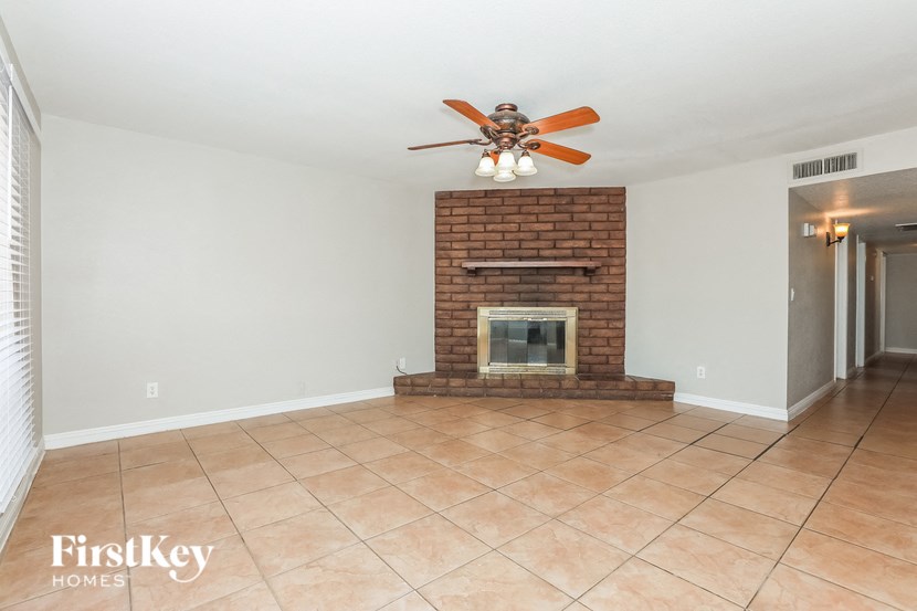 a living room with a brick fireplace and a ceiling fan