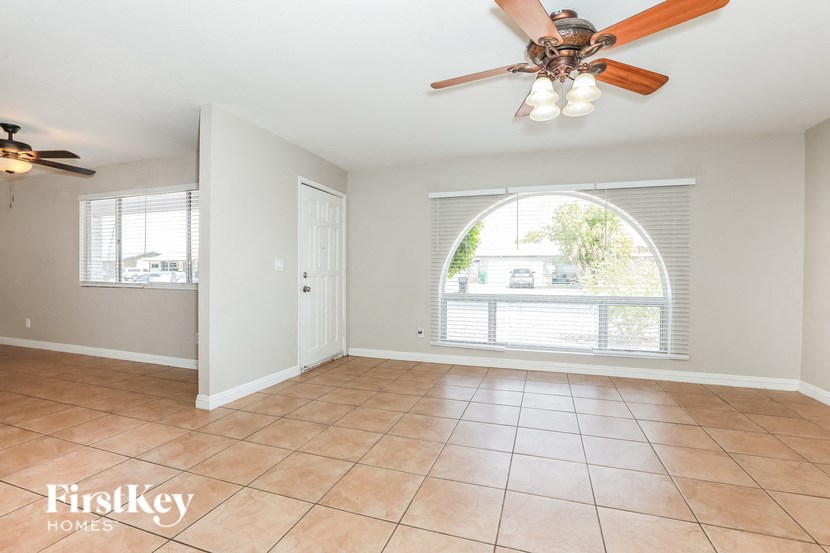 an empty living room with a ceiling fan and a window