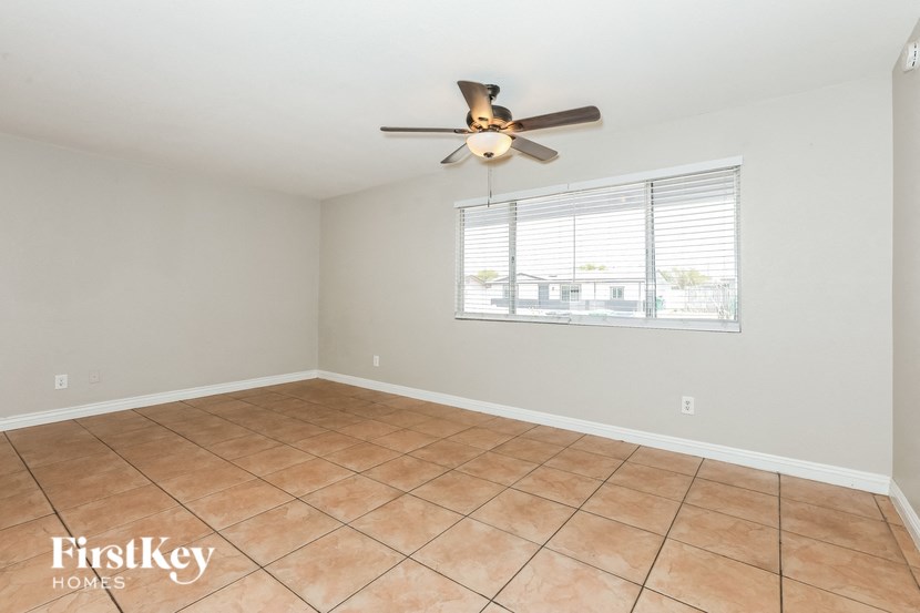 an empty living room with a ceiling fan and a window