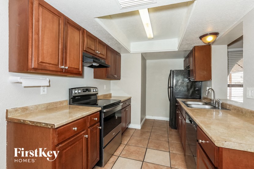 a kitchen with wood cabinets and black appliances and a sink
