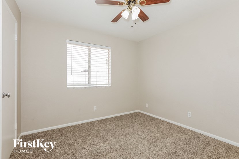 an empty room with a ceiling fan and a window