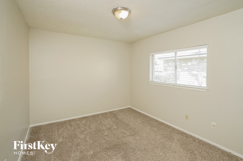 an empty bedroom with a window and carpeting