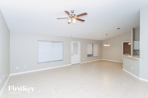 A spacious empty room with a ceiling fan and a window.