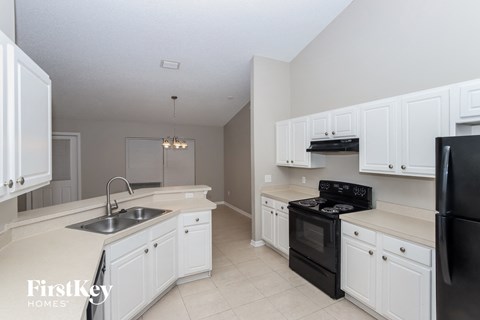 A kitchen with white cabinets and black appliances.