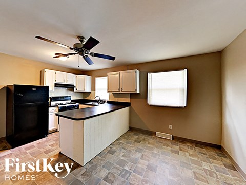 A kitchen with a black fridge and a black stove top oven.