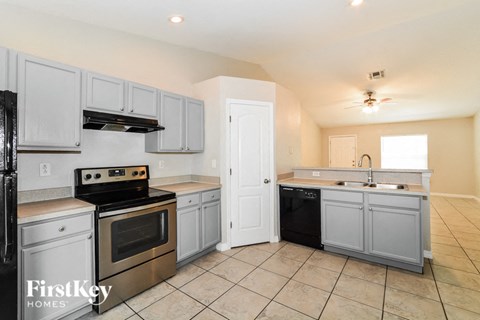 a kitchen with white cabinets and stainless steel appliances and tiled floors