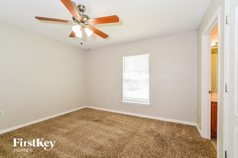 a living room with carpet and a ceiling fan