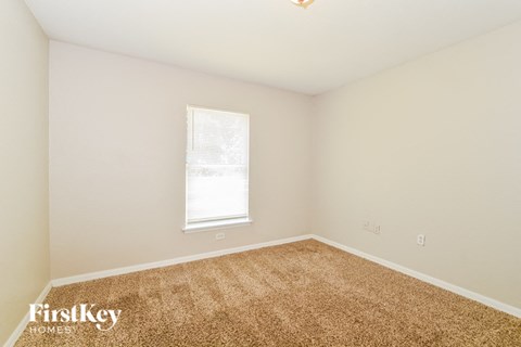 a spacious room with carpet and a window
