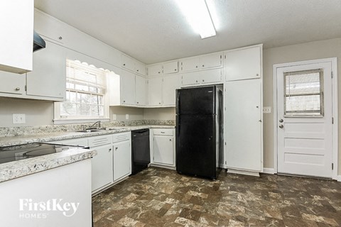 a white kitchen with white cabinets and a black refrigerator