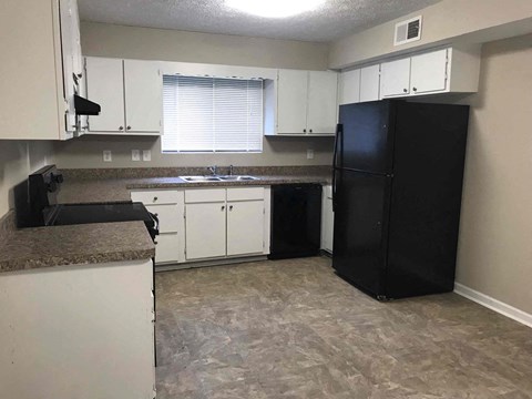 a kitchen with white cabinets and a black refrigerator