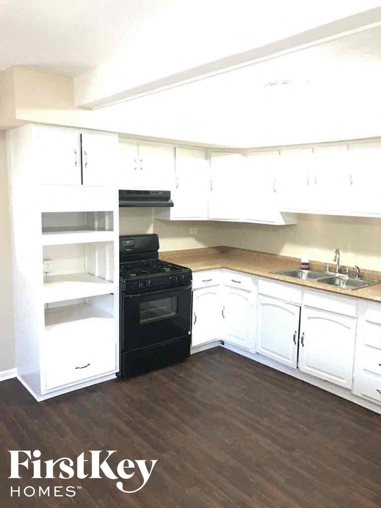 an empty kitchen with white cabinets and black appliances