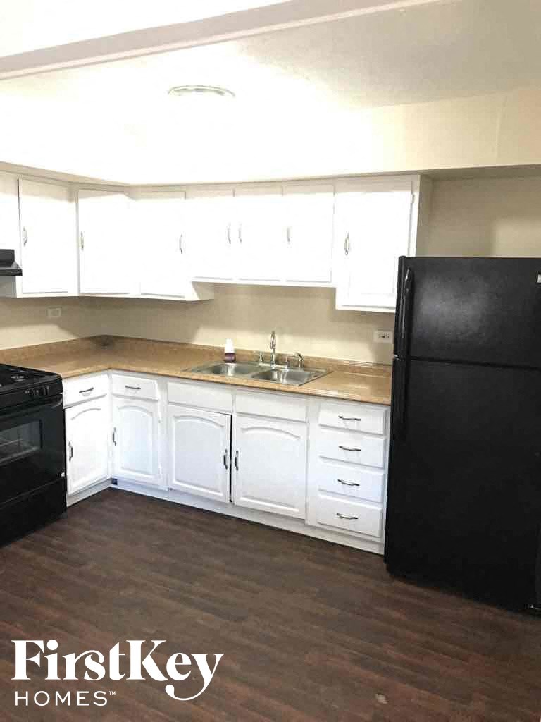 a kitchen with white cabinets and a black refrigerator