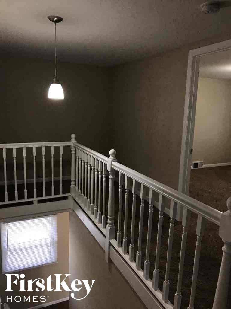 a stairway with a white railing and a ceiling light