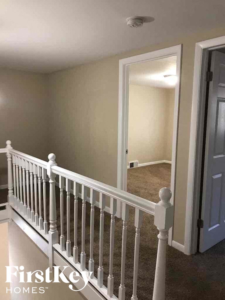 a stairway with a white railing and a hallway with a door