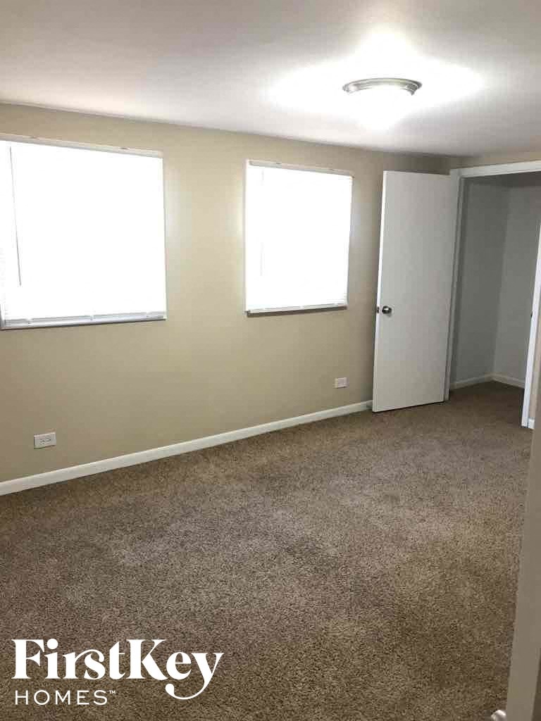 an empty room with a carpet and two windows
