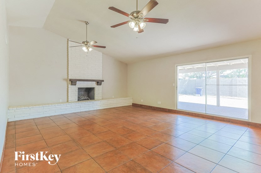 an empty living room with a fireplace and a ceiling fan