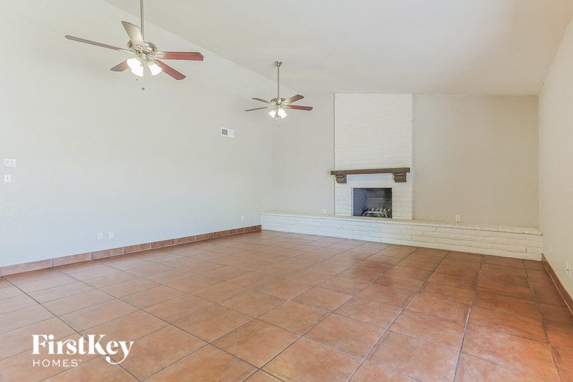 a empty living room with a fireplace and two ceiling fans
