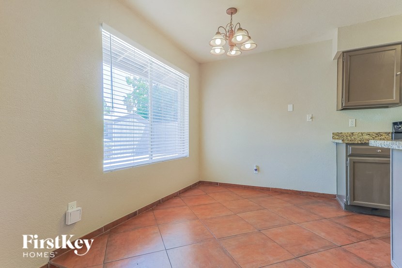 an empty living room with a kitchen and a large window